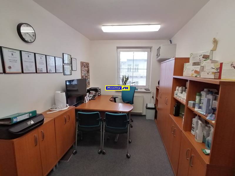 Kanceláře s nábytkem, certifikáty na stěně a policemi s produkty.