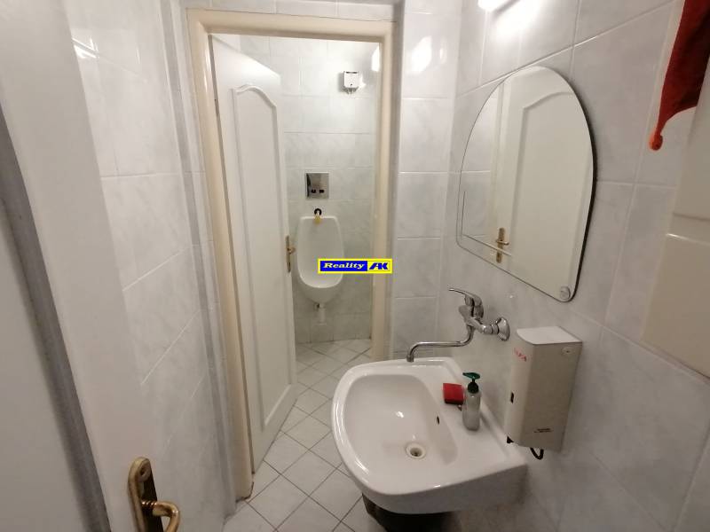 Malá koupelna s umyvadlem a pisoárem v kancelářích.