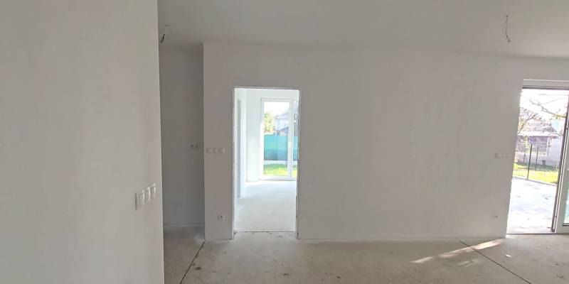 Rodinný dům se světlou místností, bílými stěnami a velkými okny do zahrady.