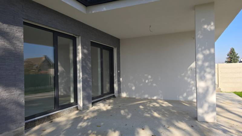 Terasa rodinného domu v Piešťanech s velkými okny a kamenným dekorem.