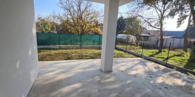 Rodinný dům v Piešťanech se zahradou, oplocený dvůr s trávníkem a stromy na pozemku.