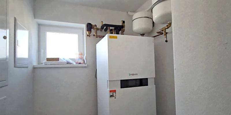 Kondenzační kotel ve světlé technické místnosti rodinného domu s oknem.