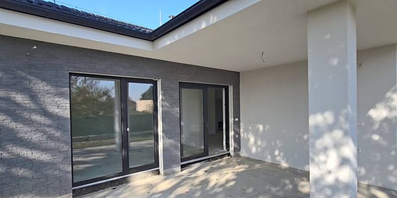 Terasa rodinného domu v Piešťanech s velkými prosklenými dveřmi a šedými stěnami.