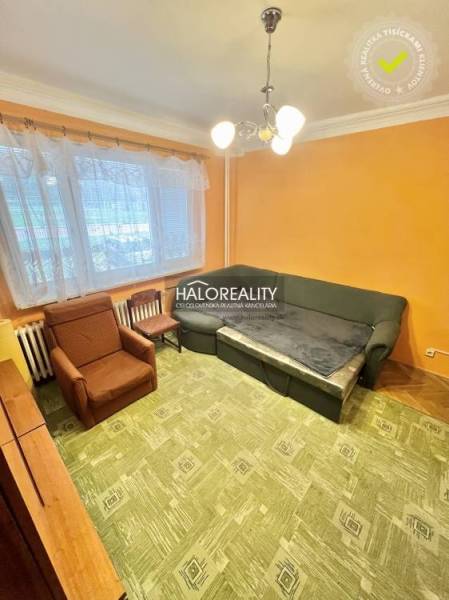 Obývací pokoj ve čtyřpokojovém bytě s oranžovými stěnami a zeleným kobercem.