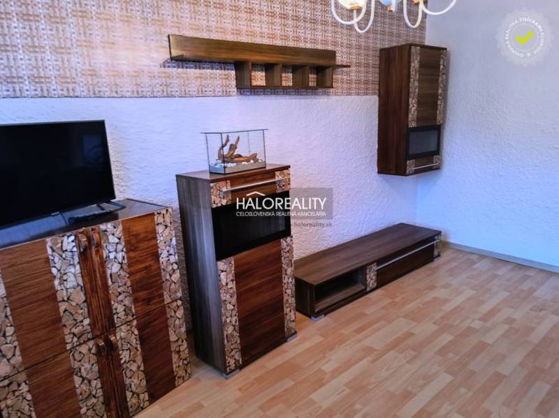 Obývací pokoj v 3-pokojovém bytě s televizí a podlahou s dřevěným dekorem.