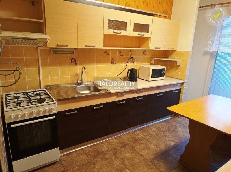 Kuchyně v 3-pokojovém bytě s plynovým sporákem a podlahou s dřevěným dekorem.