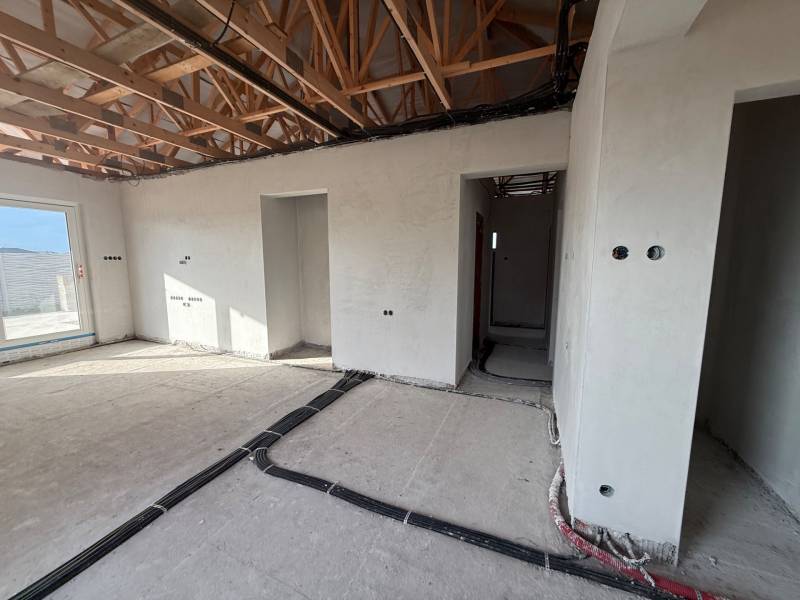 Interiér rodinného domu s rozestavěnými stěnami a podlahou s dřevěným dekorem.