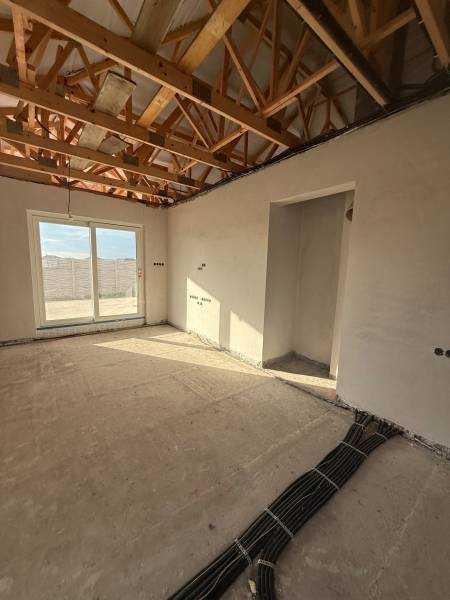 Interiér rodinného domu s odhalenými stropními trámy a přípravou elektroinstalace.