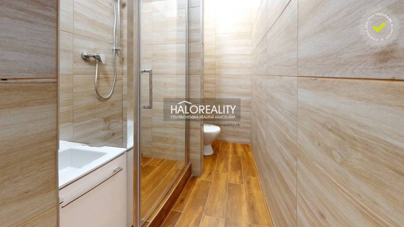 Koupelna v 1-pokojovém bytě se sprchovým koutem a podlahou s dřevěným dekorem.