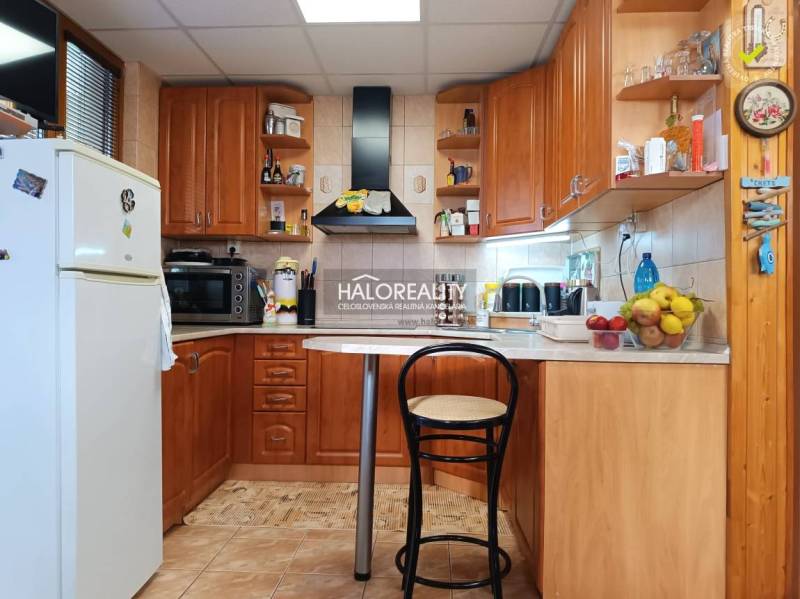 Kuchyně v chatě s dřevěným dekorem, barovým pultem a spotřebiči.