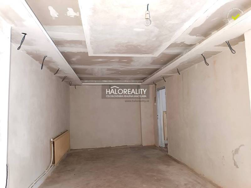 Nezařízená místnost v rodinném domě s bílými stěnami a cihlovou podlahou.