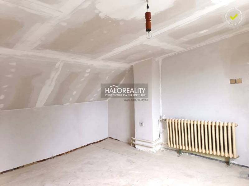 Interiér s bílým stropem, radiátorem a podlahou v rodinném domě.