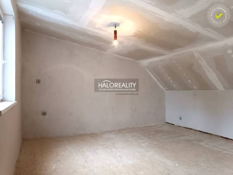 Neposkytnutý podkrovní prostor v rodinném domě, světlé stěny a dřevěná podlaha.