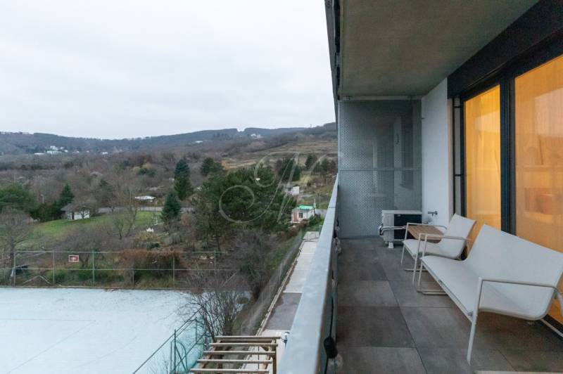 Balkon v 1-pokojovém bytě, výhled na přírodu, pohled na zahrady a stromy.