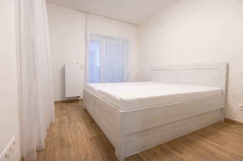 Ložnice v 2-pokojovém bytě s postelí a podlahou s dřevěným dekorem.