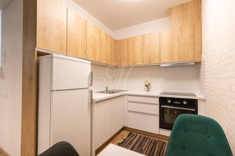 Kuchyně v 2-pokojovém bytě s dřevěným dekorem a bílými skříňkami.