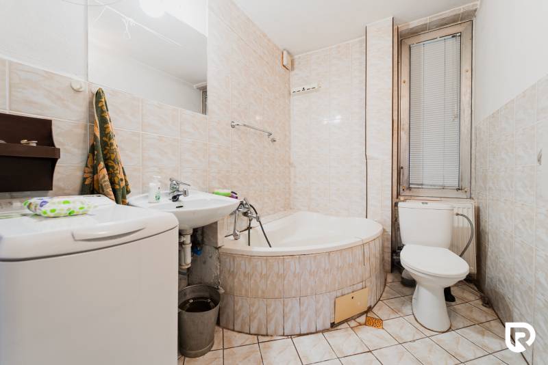 Koupelna s vanou, umyvadlem a pračkou v rodinném domě.