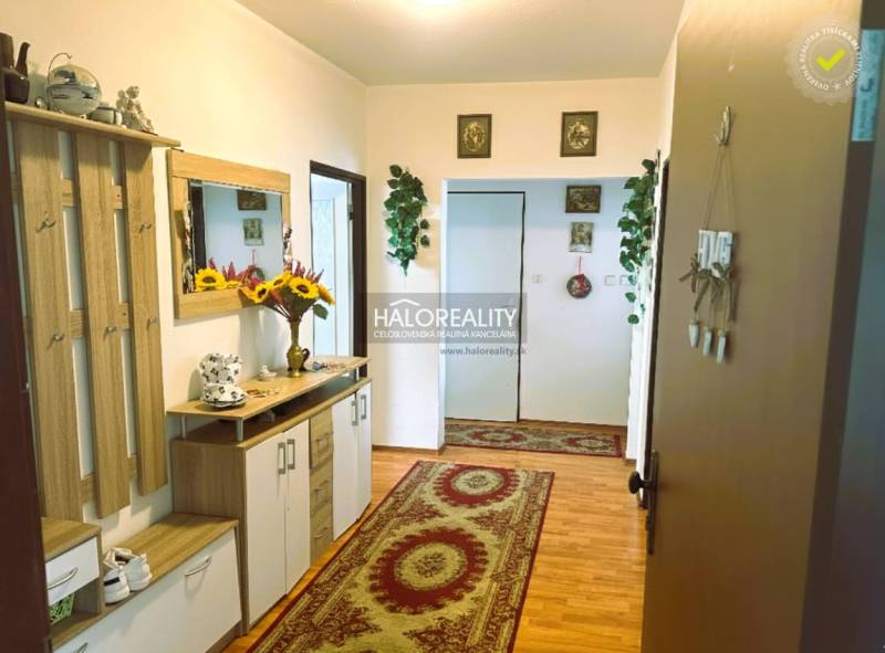 Chodba v 3-pokojovém bytě s podlahou s dřevěným dekorem a květinovou výzdobou.