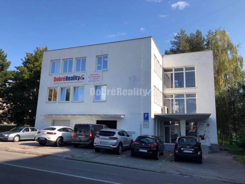 Obchodní prostory na ulici Dlhá v Prievidzi s parkovištěm před budovou.
