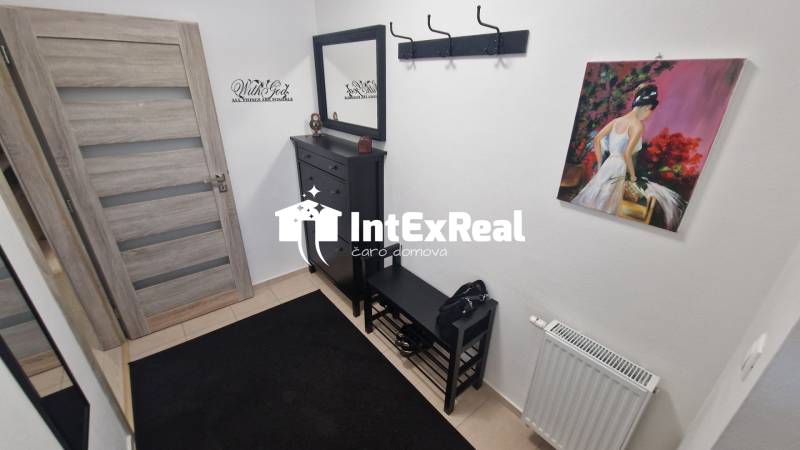 Chodba v 3-pokojovém bytě s obrazem, skříňkou a věšákem.