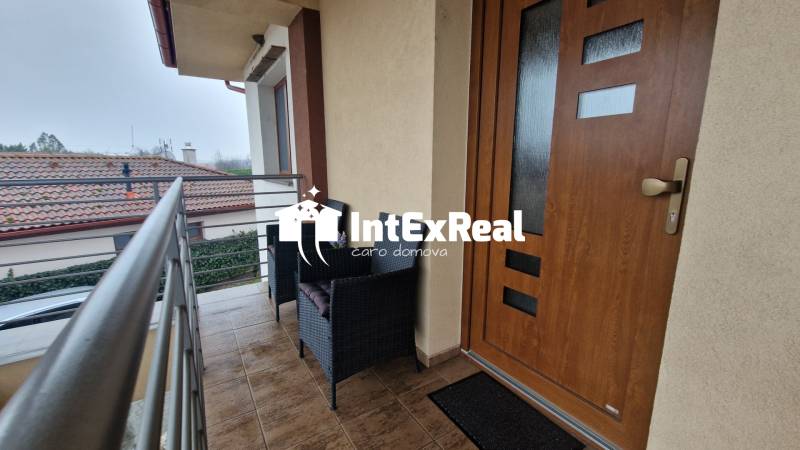 Balkon 3-pokojového bytu s posezením, výhled na Vozokany a okolní střechy.