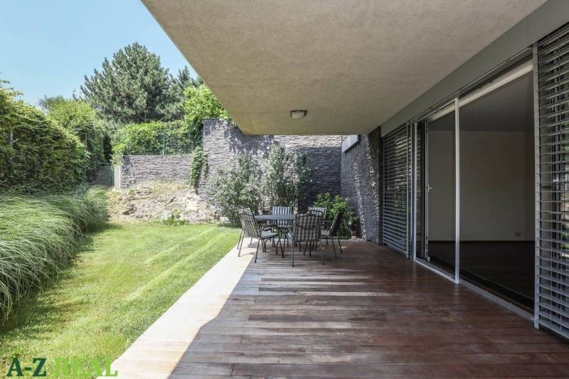 Terasa s podlahou s dřevěným dekorem, zahradním sezením a zelení u 3pokojového bytu.