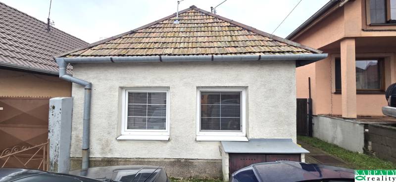 Rodinný dům v Dolních Orešanech s klasickou střechou a dvěma okny v popředí.