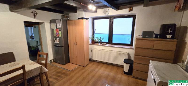 Kuchyně v rodinném domě s podlahou s dřevěným dekorem, stolem a lednicí.