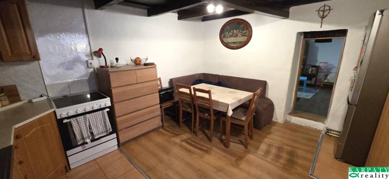 Kuchyně v rodinném domě s rohovou sedačkou a podlahou s dřevěným dekorem.