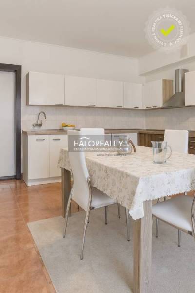 Kuchyně v rodinném domě s bílou linkou a jídelním stolem se čtyřmi židlemi.