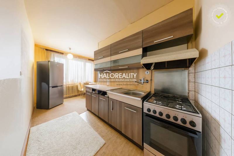 Kuchyně 3pokojového bytu s tmavými skříňkami, světlými stěnami a velkým oknem.