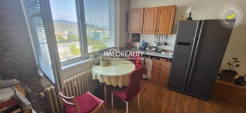 Kuchyně v 1-pokojovém bytě se stolem, židlemi a výhledem z okna.