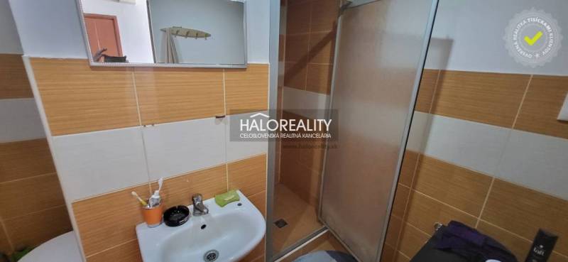 Koupelna s umyvadlem a sprchou v 1-pokojovém bytě, oranžovo-bílé obklady.