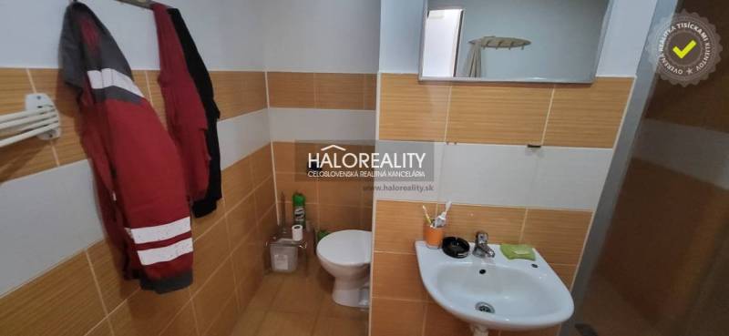 Koupelna s toaletou a umyvadlem v 1-pokojovém bytě s obklady v teplých tónech.