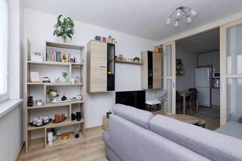 Obývací pokoj v 2-pokojovém bytě s vestavěným nábytkem a podlahou s dřevěným dekorem.