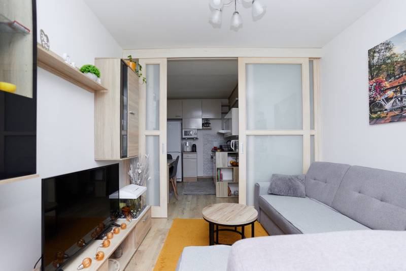 Obývací pokoj v 2pokojovém bytě s kuchyní a podlahou s dřevěným dekorem.