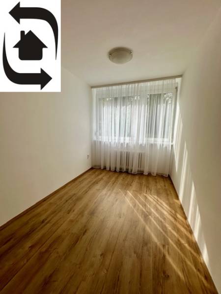 Pokoj s podlahou s dřevěným dekorem ve 3-pokojovém bytě, záclony na okně.