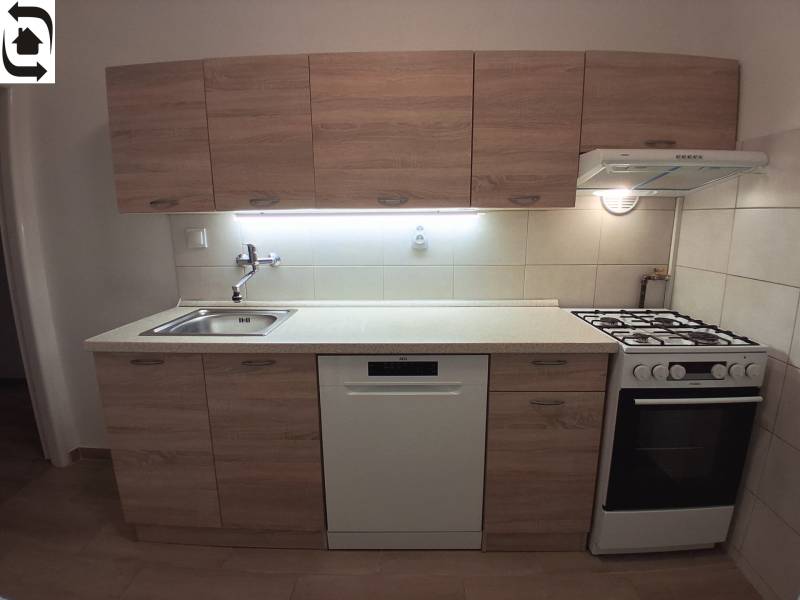 Kuchyně s dřevěným dekorem, dřezem, myčkou a sporákem v 3-pokojovém bytě.