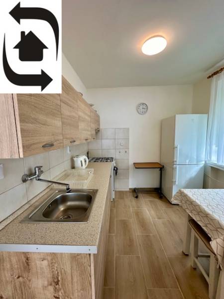 Kuchyně v 3-pokojovém bytě s podlahou s dřevěným dekorem a bílými stěnami.