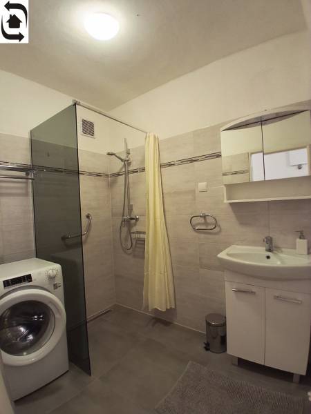 Koupelna se sprchovým koutem, pračkou a zrcadlovou skříňkou v 3-pokojovém bytě.