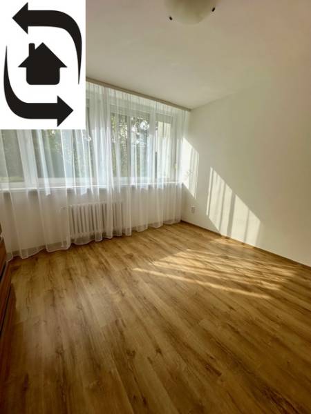 Pokoj v 3-pokojovém bytě s podlahou s dřevěným dekorem a velkým oknem.