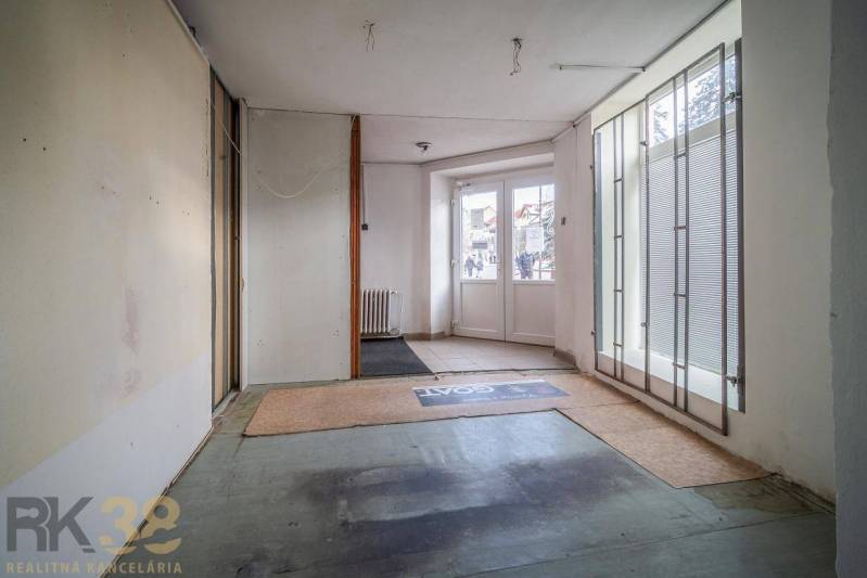 Interiér budovy se skleněnými dveřmi a matnými roletami, podlaha s kobercem.