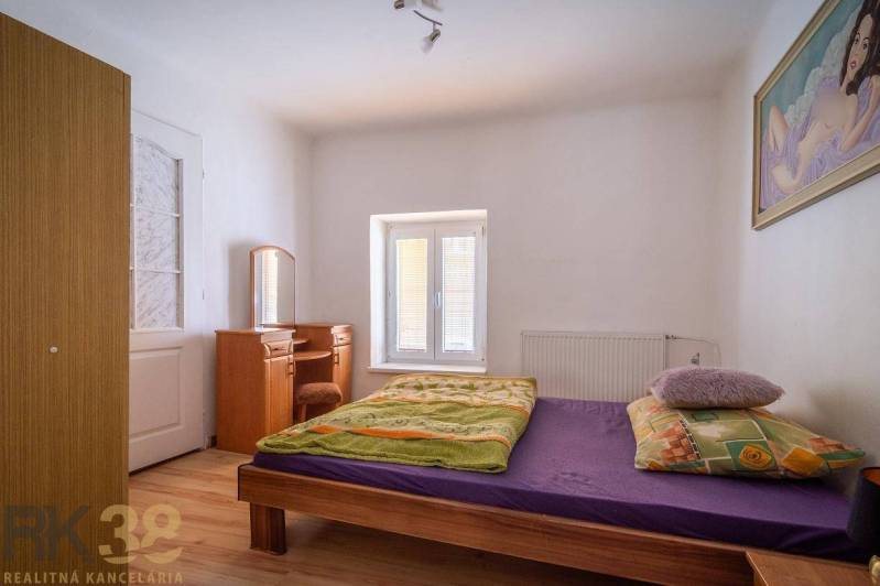 Ložnice s postelí, zrcadlem a podlahou s dřevěným dekorem.