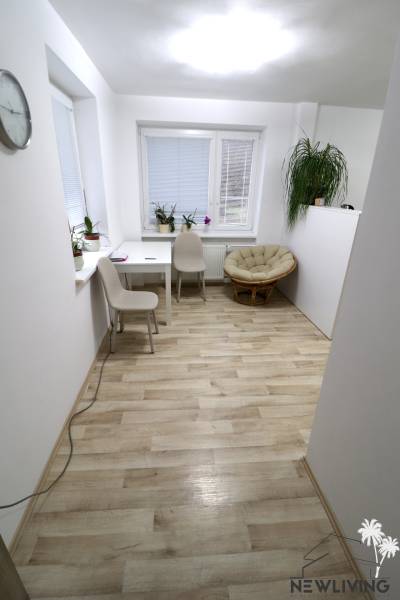 Pokoj v rodinném domě s podlahou s dřevěným dekorem, světlým nábytkem a rostlinami.