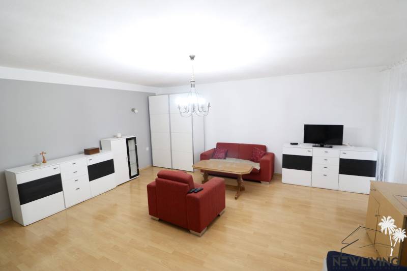 Obývací pokoj v rodinném domě s podlahou s dřevěným dekorem a červenou sedačkou.