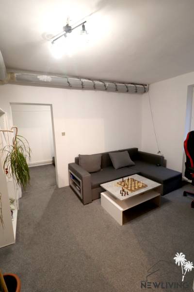 Obývací pokoj s pohovkou, šachovnicí a kobercem v rodinném domě.