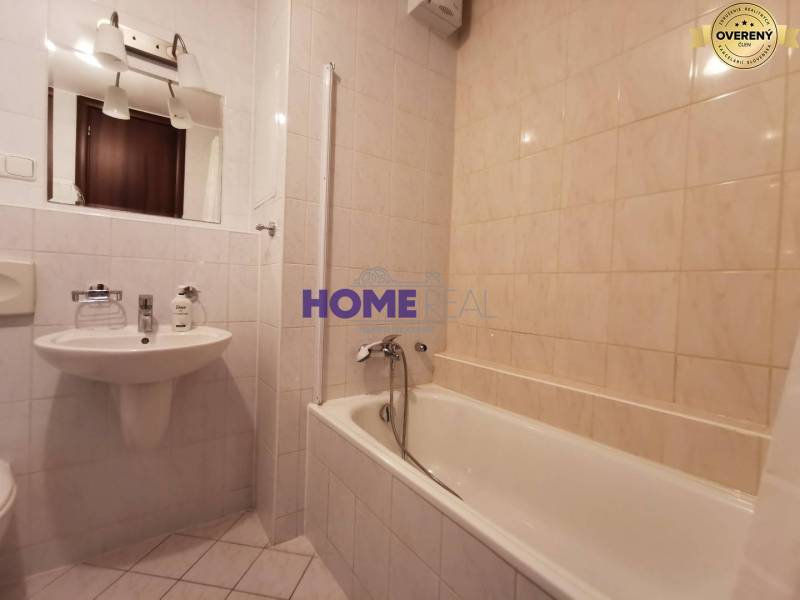 Koupelna v 2-pokojovém bytě s vanou, umyvadlem a zrcadlem.