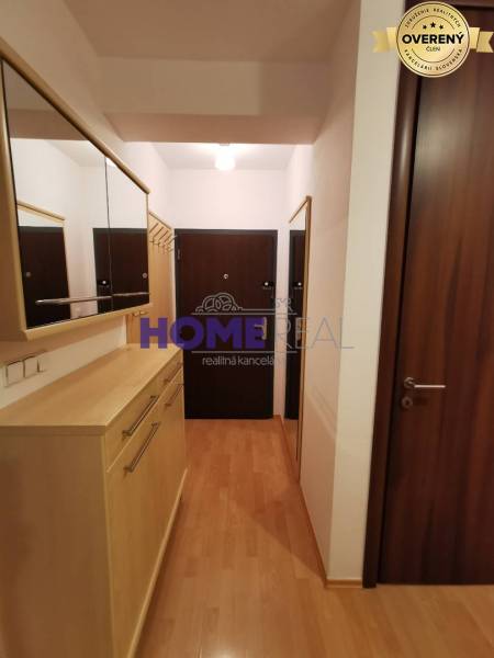 Předsíň v 2-pokojovém bytě s podlahou s dřevěným dekorem, zrcadly a skříněmi.