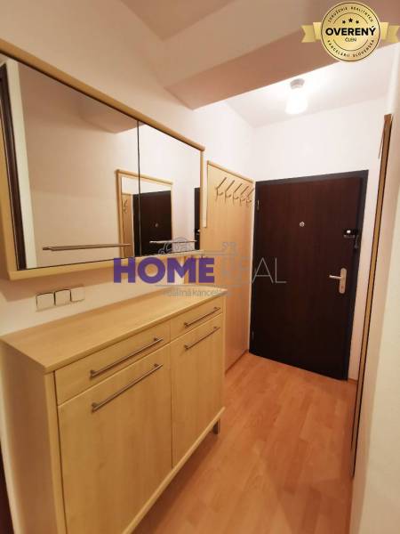 Chodba v 2-pokojovém bytě s podlahou s dřevěným dekorem, zrcadlem a skříňkou.