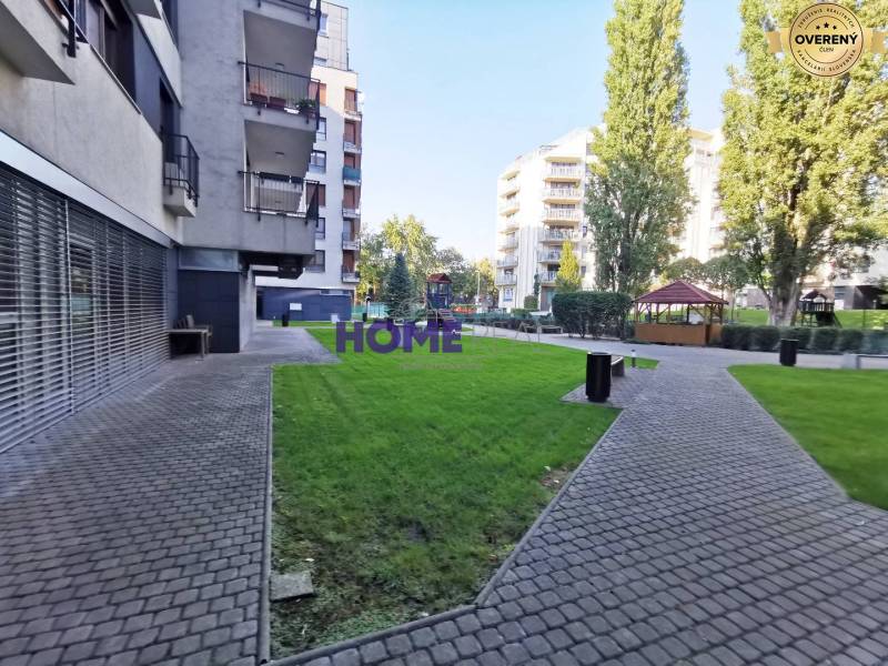 Pohled na obytnou zónu s chodníkem a zelenými trávníky v Bratislavě na Drieňové.